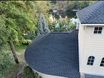 Curved shingle roof on a lakeside home, aerial view of a DG Contracting installation